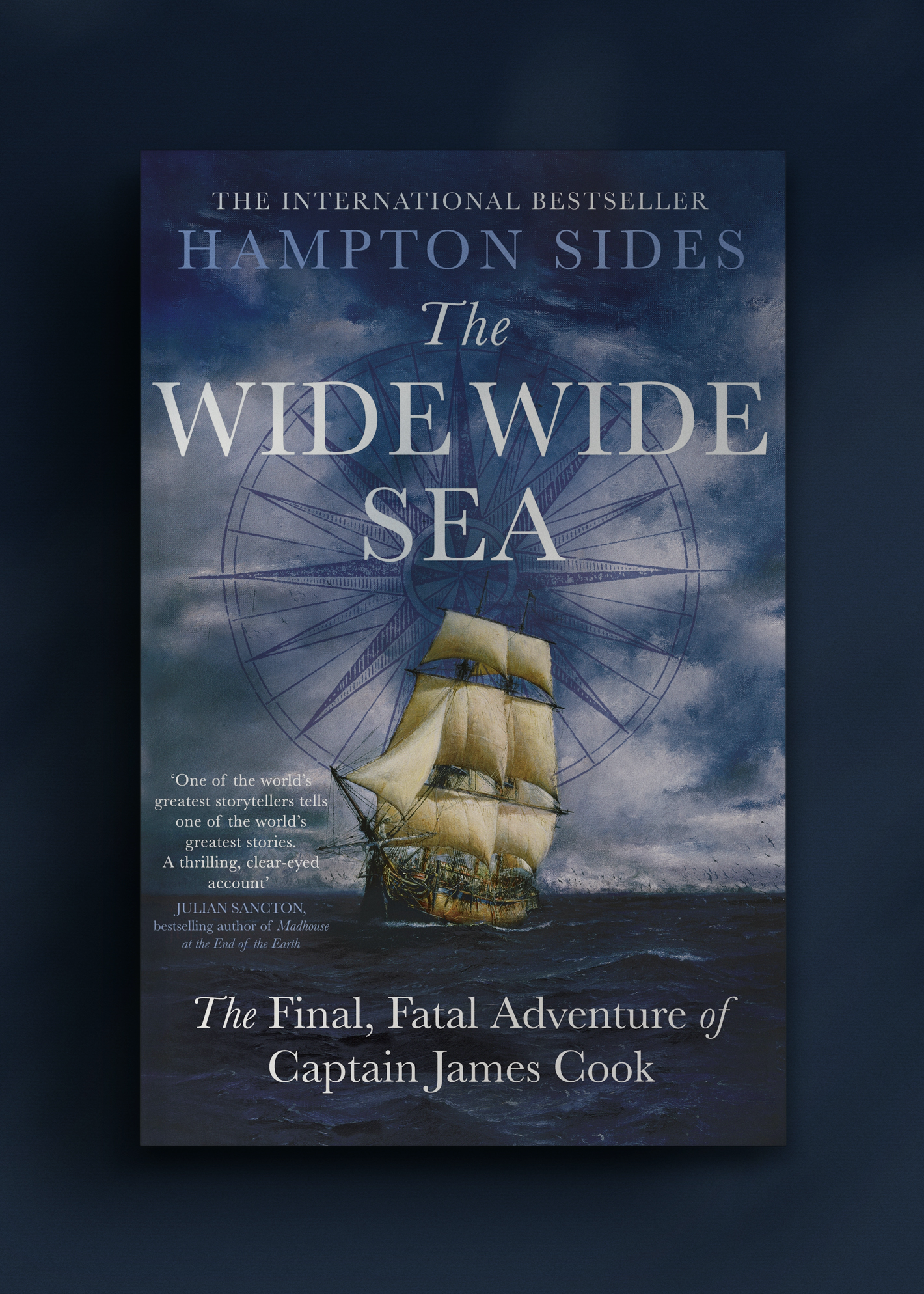 A book cover titled "The Wide Wide Sea" by Hampton Sides. Features a sailing ship on stormy waters, set against a compass rose superimposed on a brooding dark sky.